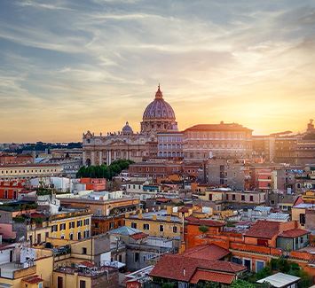 Bild bestehend aus einem Luftbildplan der Stadt Rom. Im Vordergrund sind mehrere Wohngebäude zu sehen, während der Hintergrund aus mehreren römischen Denkmälern und dem hinter diesen zu sehenden Sonnenuntergang besteht.